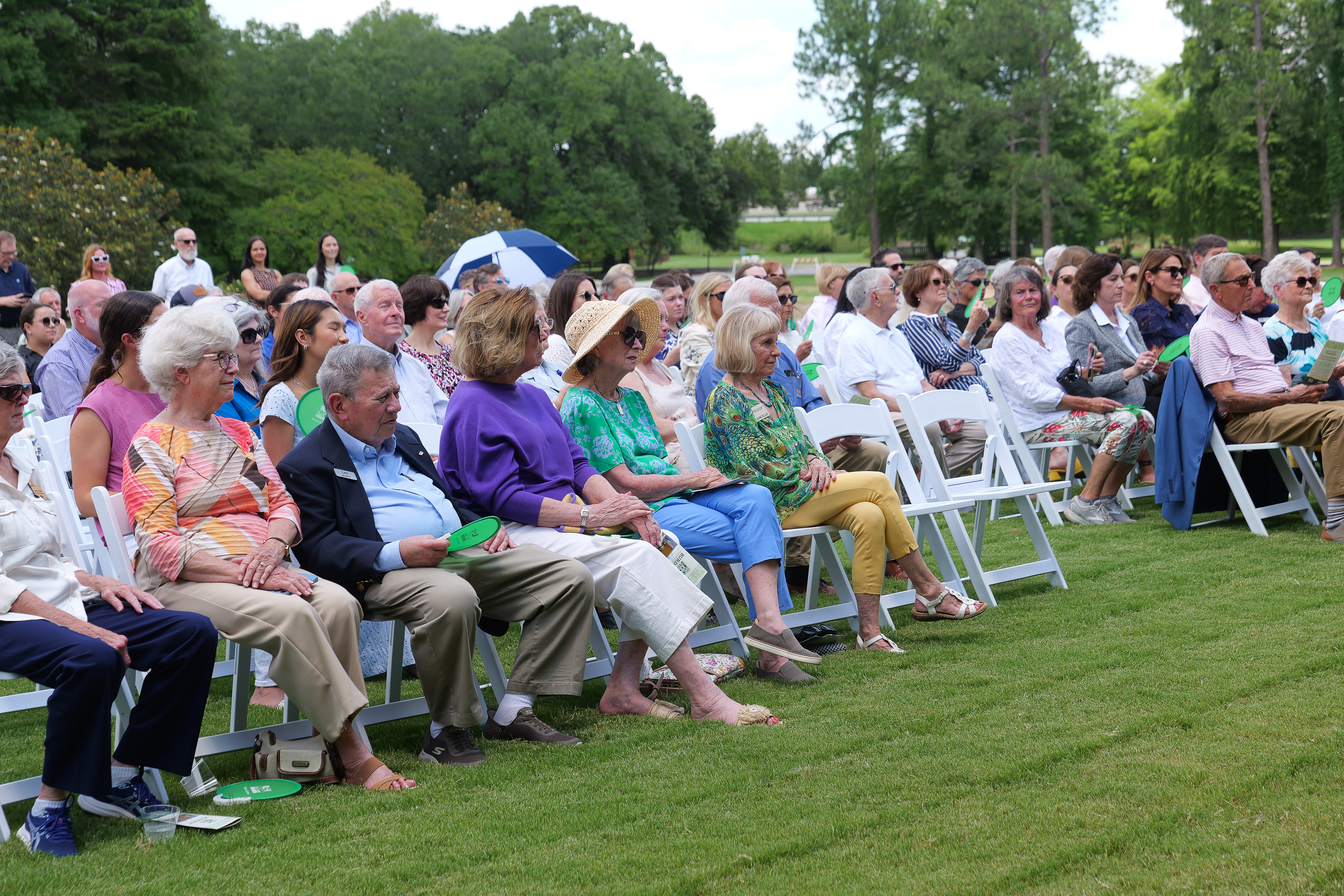 Audience seated in folding chairs on a lawn.